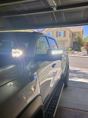 Low quality picture of a spotlight and LED Side Mirrors, both installed on a RAM TRX.
