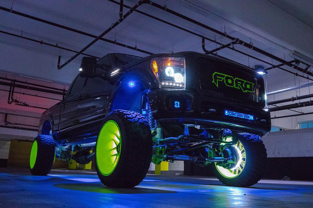 Low aggressive shot of a Ford Superduty with multiple ORACLE Lighting products installed, including LED illuminated wheel rings, headlight halo rings, and rock lights.