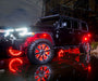 A three quarters view of a black Jeep parked in a puddle, with multiple ORACLE Lighting products installed. All of the LED lighting is turned on and shining brightly, including rock lights, wheel rings, and Vector Grill.
