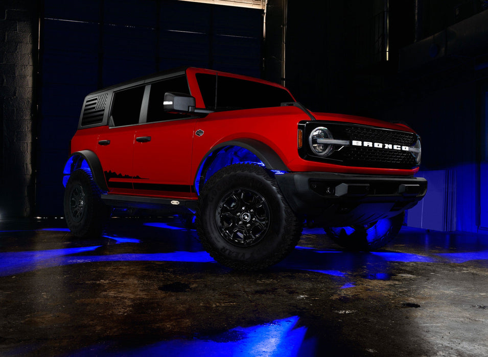 Three quarters view of a red Ford Bronco with rock lights glowing blue.