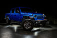 Three quarters view of a blue Jeep Gladiator JT with rock lights set to white.