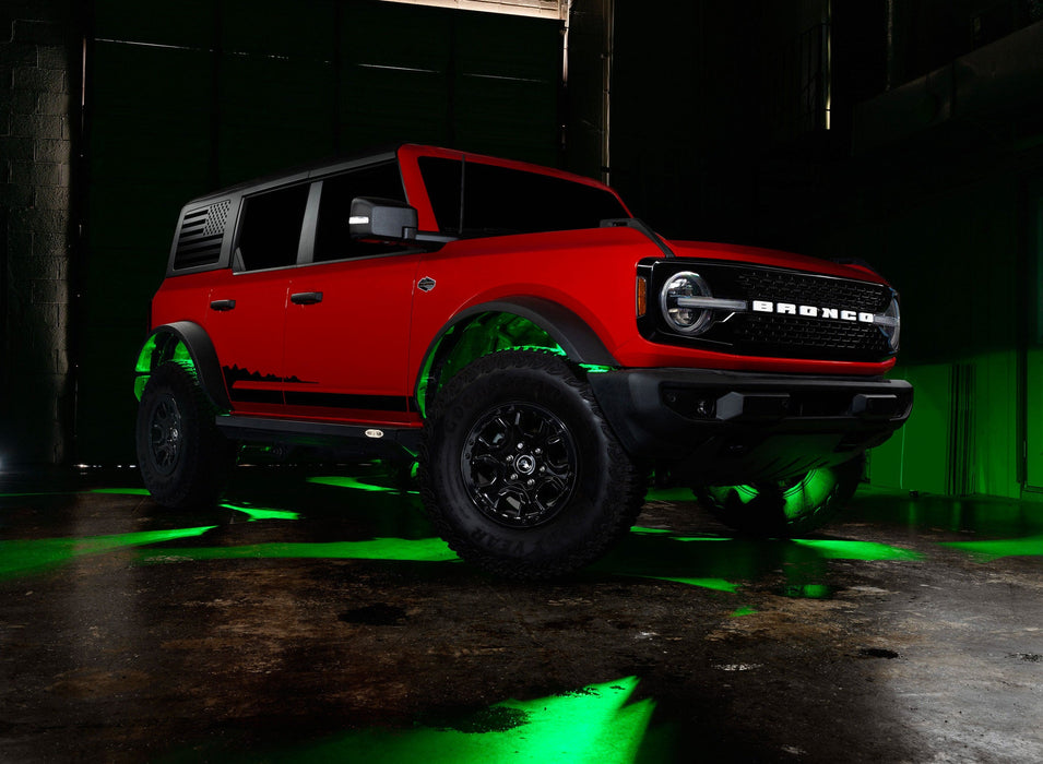 Three quarters view of a red Ford Bronco with rock lights glowing green.