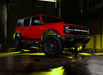 Three quarters view of a red Ford Bronco with rock lights glowing yellow.