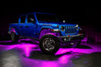 Three quarters view of a blue Jeep Gladiator JT with rock lights set to pink.