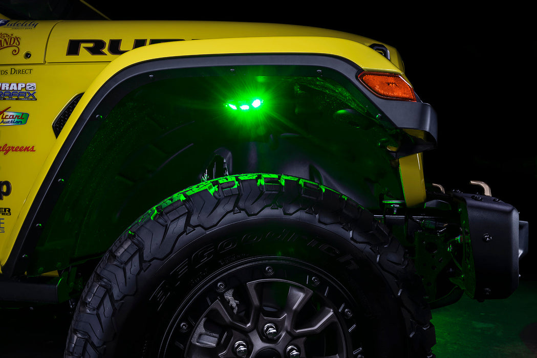 Close up on the front wheel well of a yellow jeep, with rock lights set to green LED.