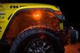 Close up on the front wheel well of a yellow jeep, with rock lights set to amber LED.
