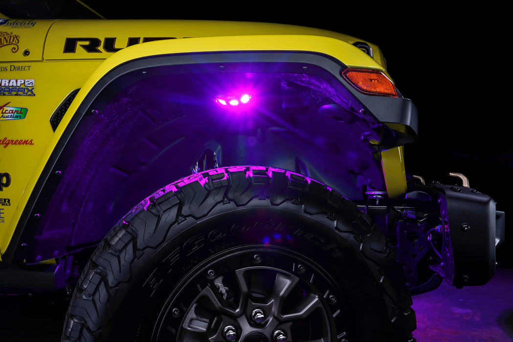 Close up on the front wheel well of a yellow jeep, with rock lights set to pink LED.