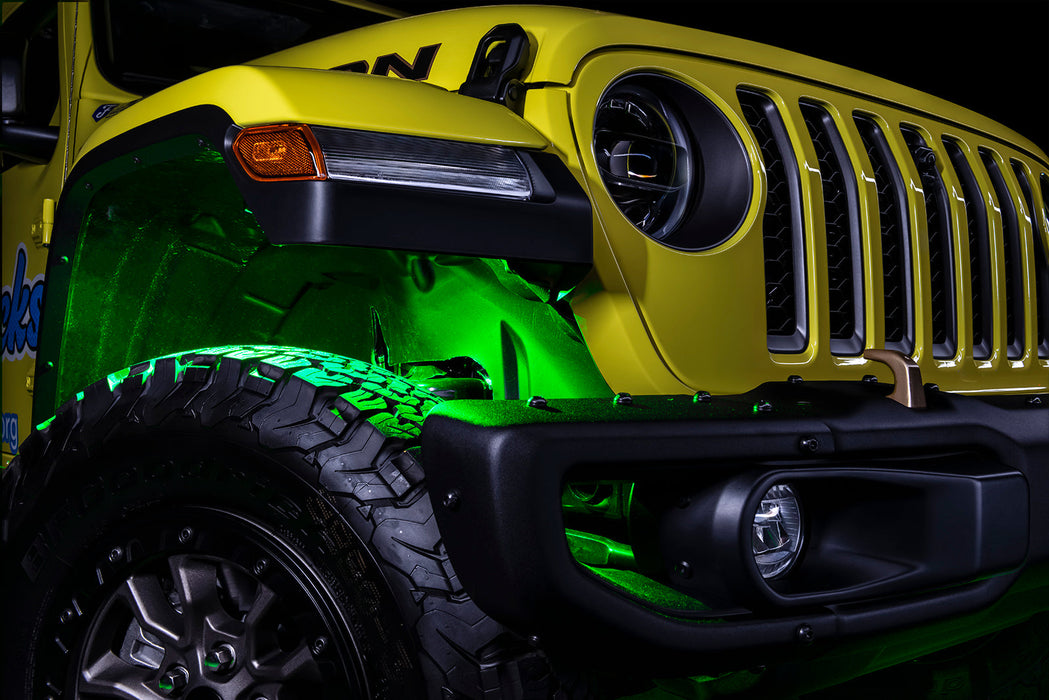 Three quarters view of the front wheel well of a jeep, with green rock lights glowing.