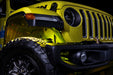 Three quarters view of the front wheel well of a jeep, with yellow rock lights glowing.