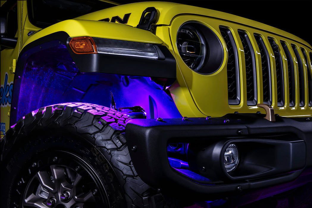 Three quarters view of the front wheel well of a jeep, with purple rock lights glowing.