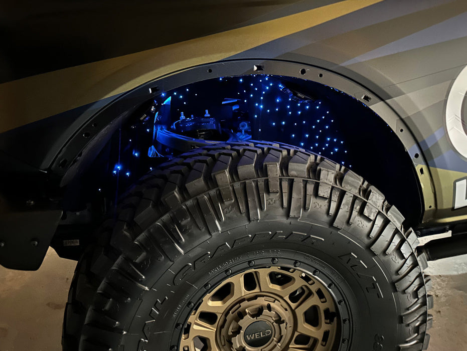 Close-up of fiber optic wheel liner kit installed on bronco with cyan LED lighting.