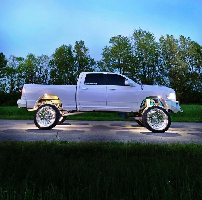 Side view of a white truck with white wheel rings and rock lights.
