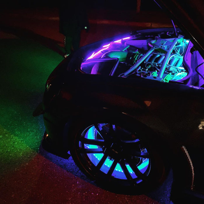 Top view of the engine bay of a car, illuminated by LED light strips. Wheel rings are also installed and set to cyan.