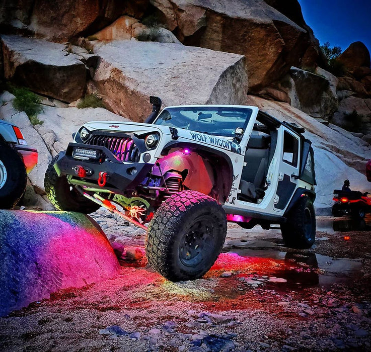 A white Jeep on a trail, with multiple aftermarket products installed, including Underbody Wheel Well Rock Lights.