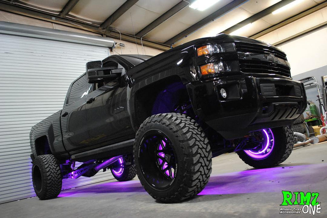 Low aggressive shot of a black Chevrolet truck with purple LED wheel rings installed.