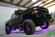 Low aggressive shot of a black Chevrolet truck with purple LED wheel rings installed.