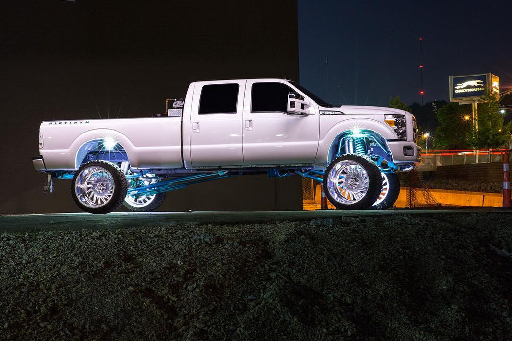 White Ford Superduty with white wheel rings and rock lights.