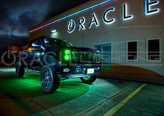 A blue truck in a parking lot, with green LED halos and green LED underbody kit.