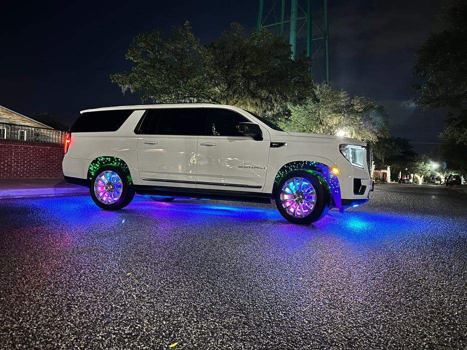 Side view of a GMC Denali with rainbow LEDs shining through the wheel wells.