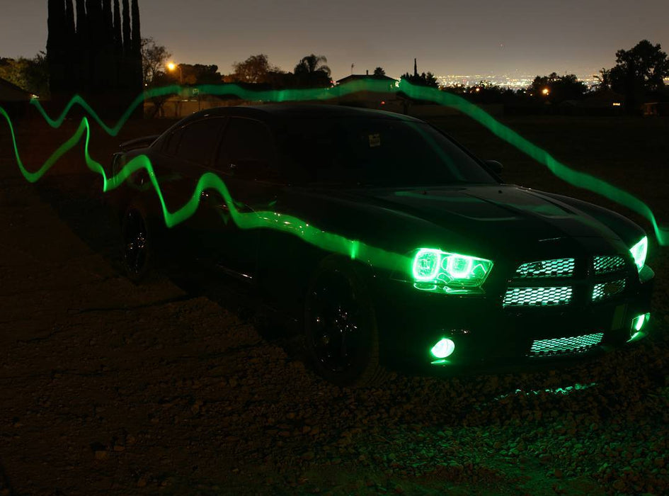 Three quarters view of a black Dodge Charger with green LED headlight and fog light halo rings installed.