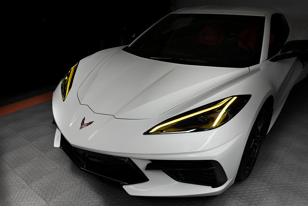 Front end of a white C8 Corvette with yellow headlight DRLs.