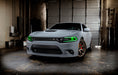 Three quarters view of a grey Dodge Charger with green headlight DRLs.