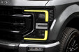 Close-up of a Ford Superduty headlight with yellow DRLs.