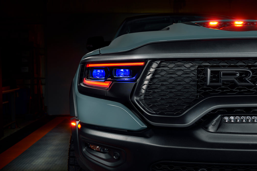 Close-up of a Ram 1500 headlight with red DRLs and blue demon eye projectors.