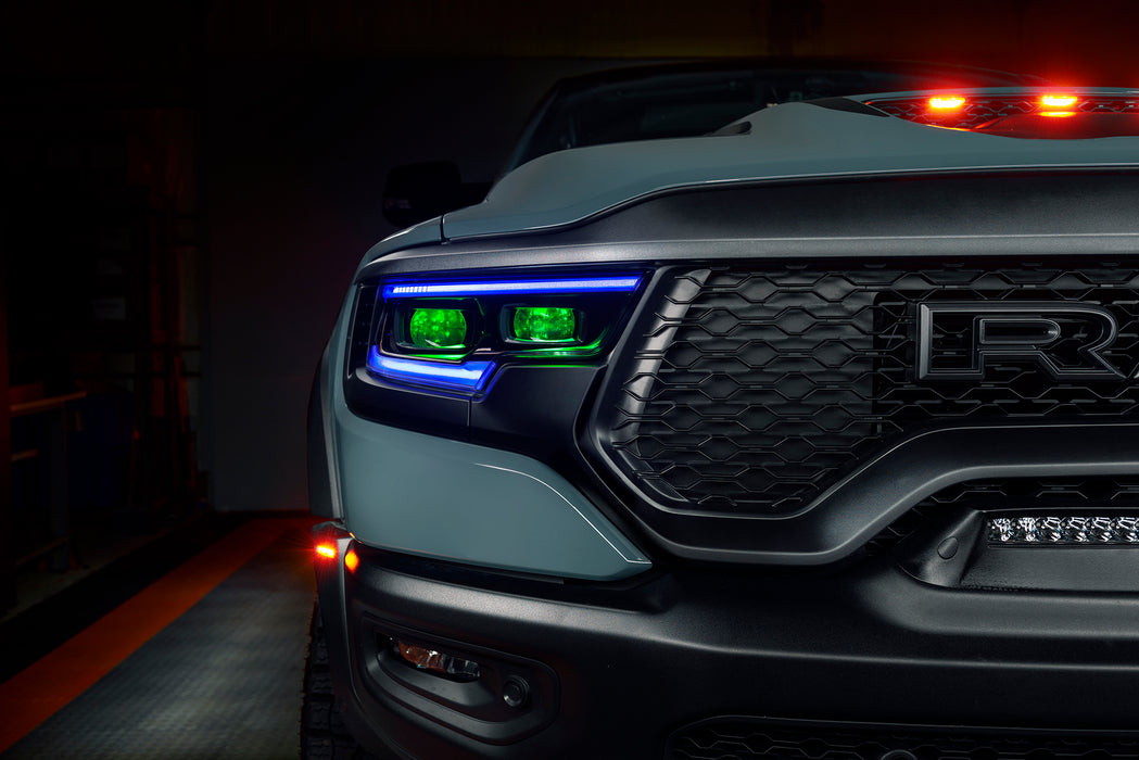 Close-up of a Ram 1500 headlight with blue DRLs and green demon eye projectors.