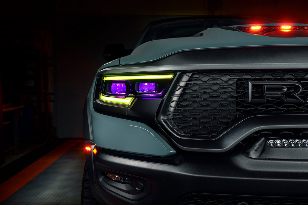 Close-up of a Ram 1500 headlight with yellow DRLs and purple demon eye projectors.