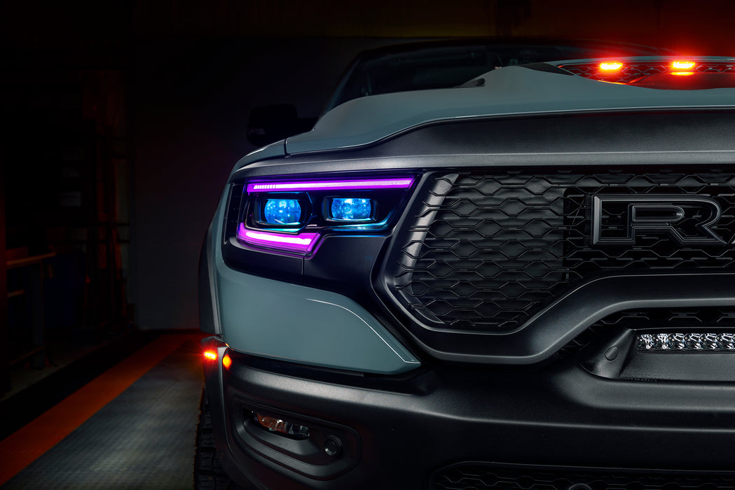 Close-up of a Ram 1500 headlight with purple DRLs and cyan demon eye projectors.