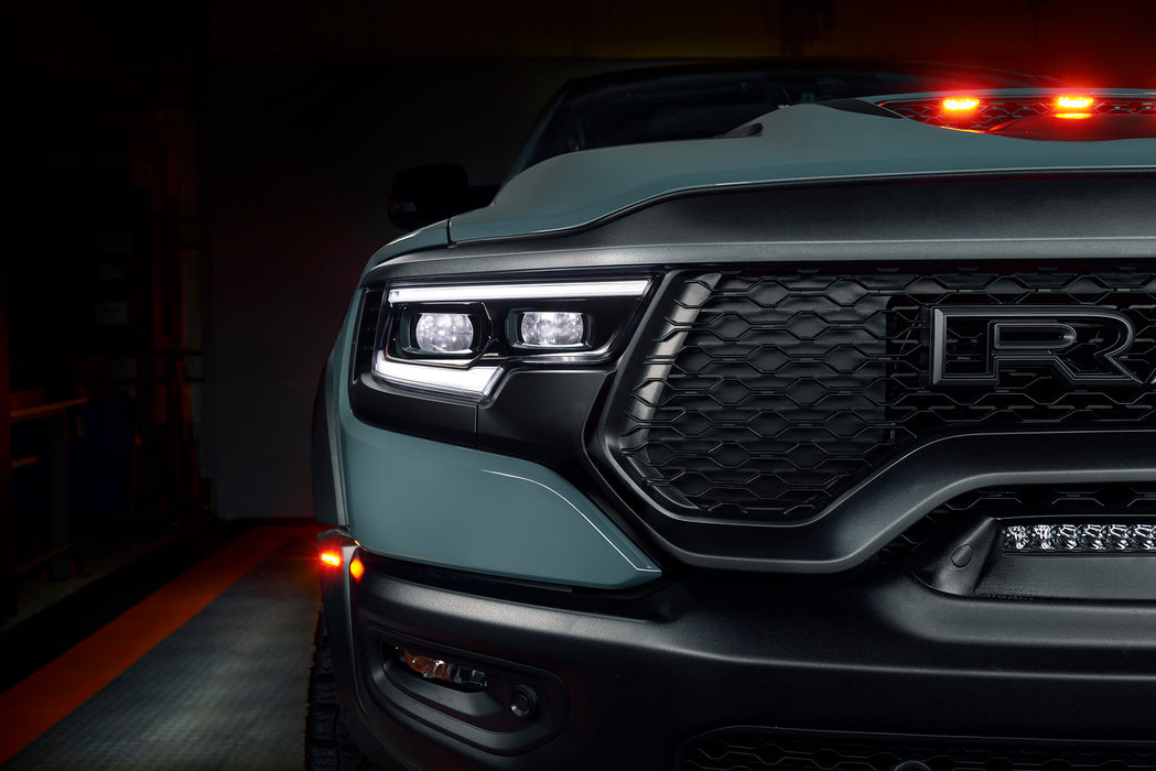 Close-up of a Ram 1500 headlight with white DRLs and white demon eye projectors.