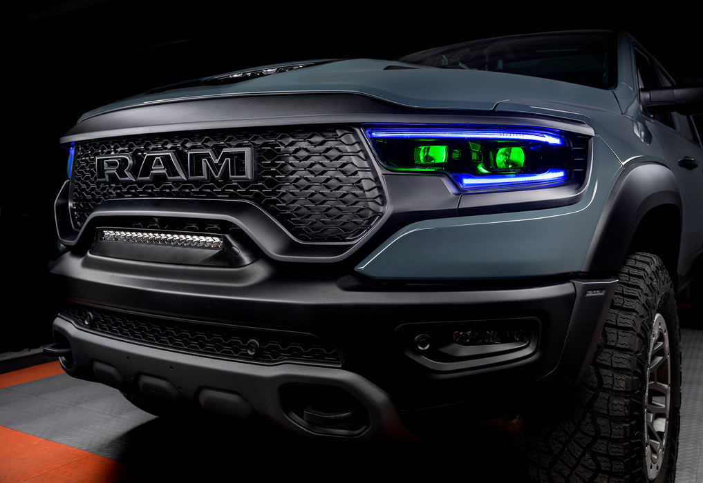 Front end of a Ram 1500 with blue headlight DRLs and green demon eye projectors.