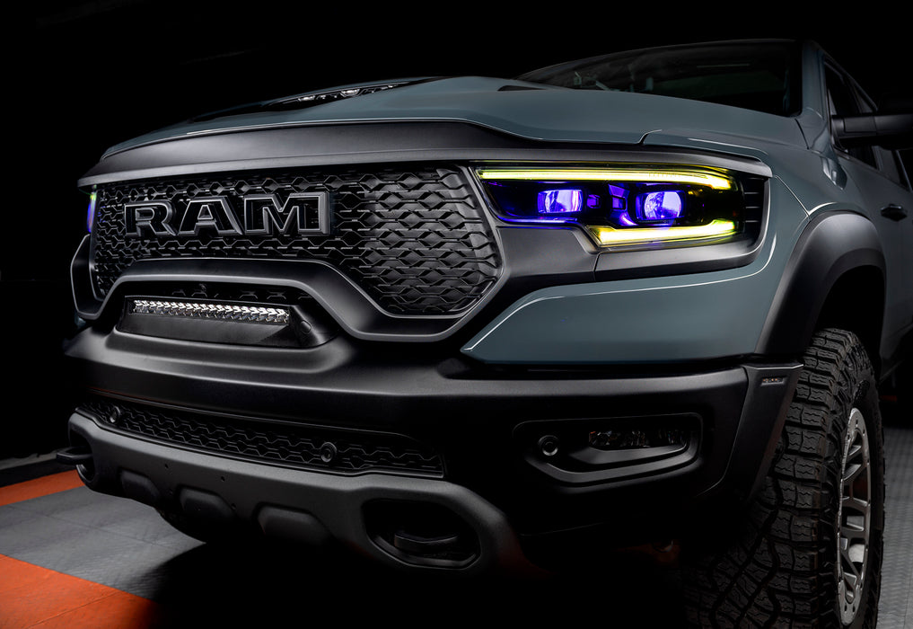 Front end of a Ram 1500 with yellow headlight DRLs and purple demon eye projectors.