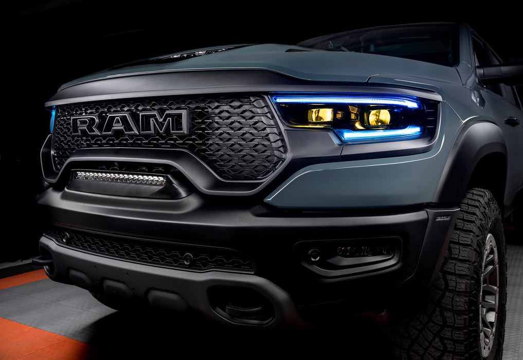 Front end of a Ram 1500 with cyan headlight DRLs and yellow demon eye projectors.