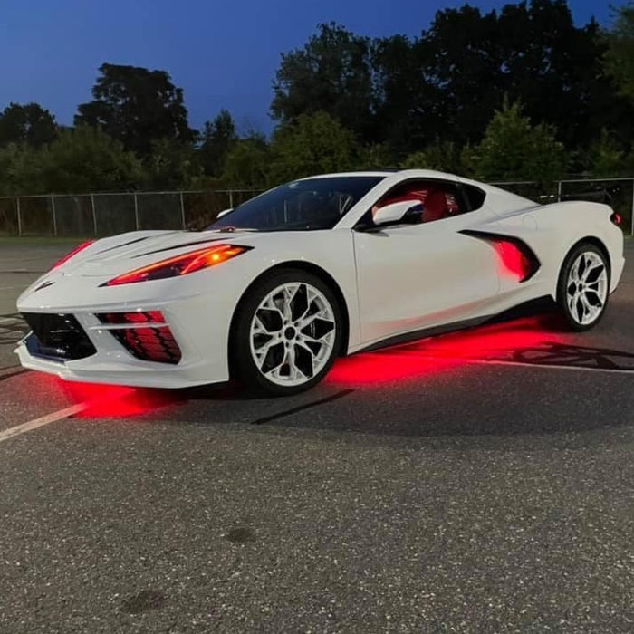 Three quarters view of a white C8 Corvette with red headlight DRLs.