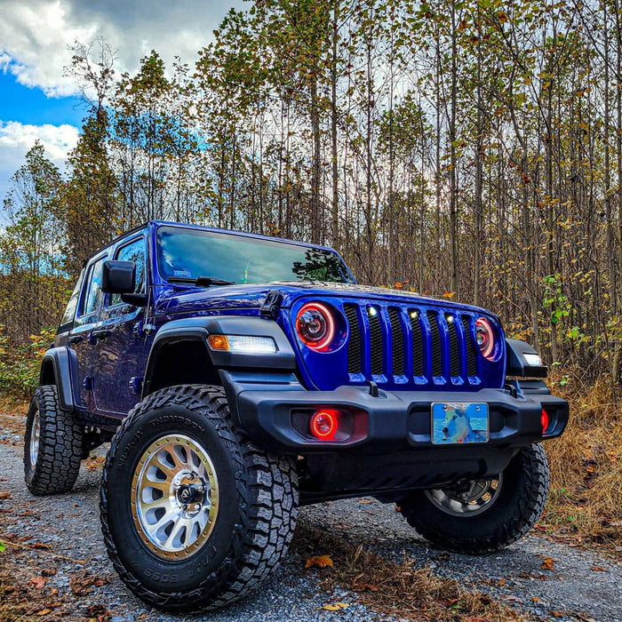 Three quarters view of a blue Jeep Wrangler JL, with ColorSHIFT Oculus Headlights installed, and red halos on.
