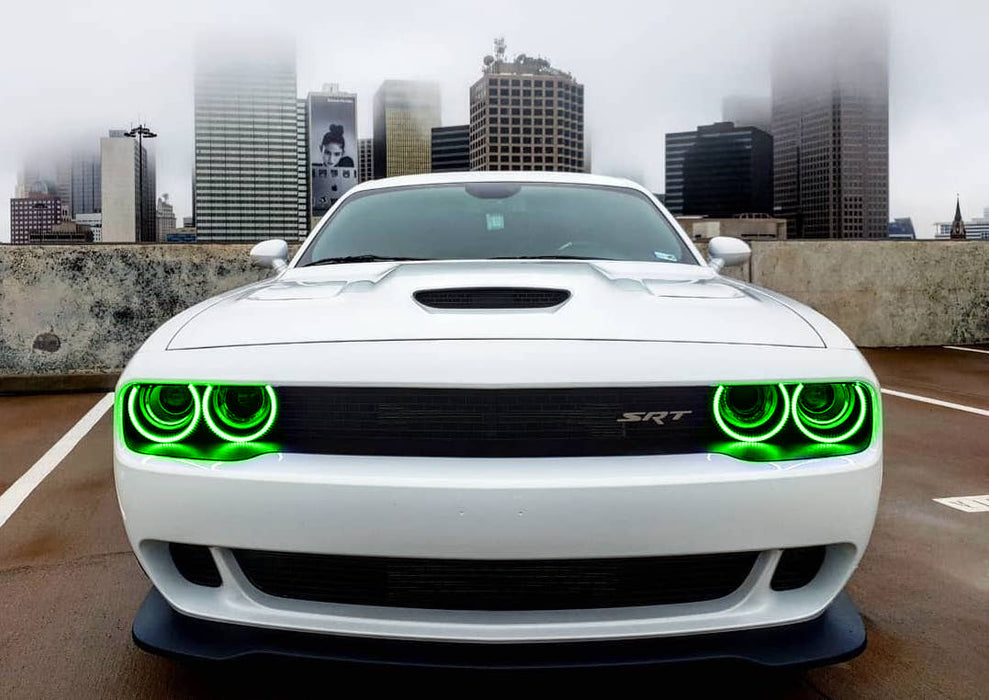 Front end of a white Dodge Challenger with green LED headlight halo rings installed.