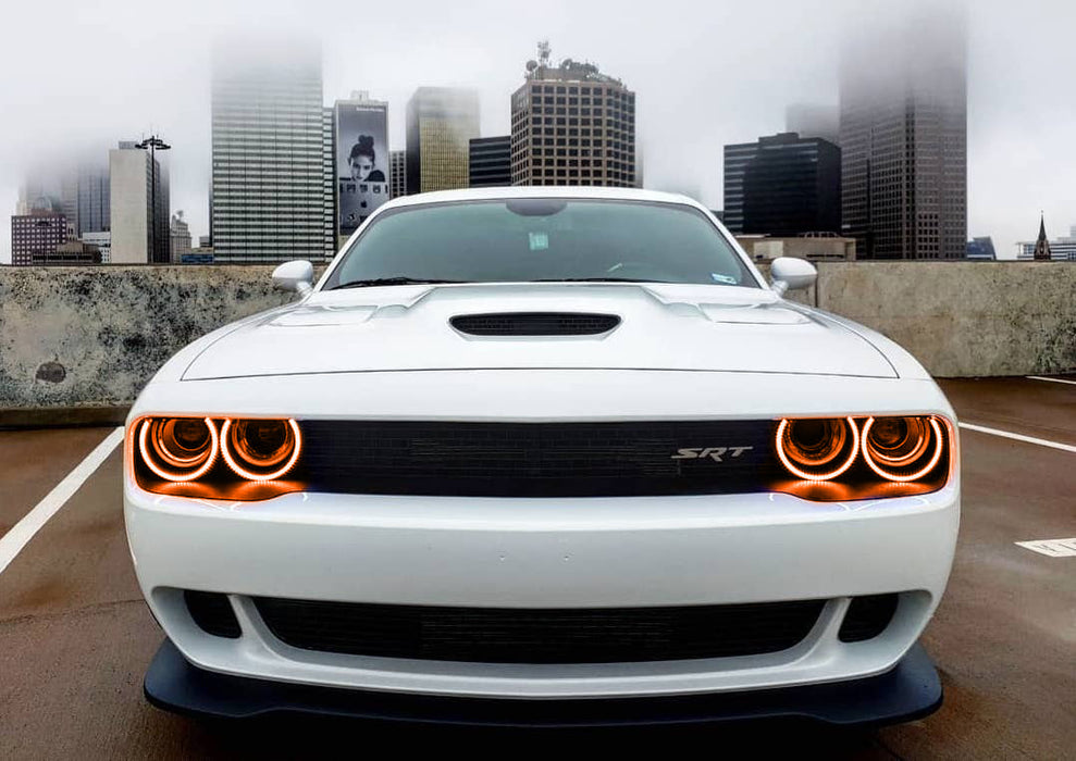 Front end of a white Dodge Challenger with amber LED headlight halo rings installed.
