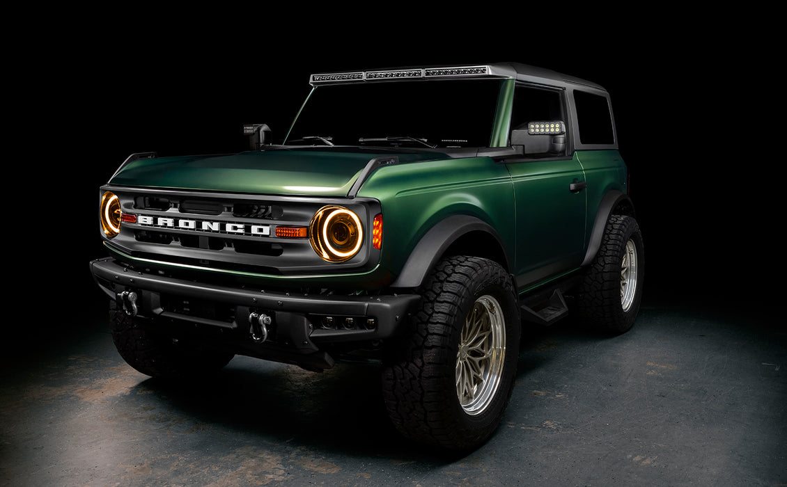 Three quarters view of a green Ford Bronco, with Oculus Headlights installed and amber DRLs on.
