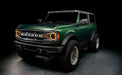 Three quarters view of a green Ford Bronco, with Oculus Headlights installed and amber DRLs on.