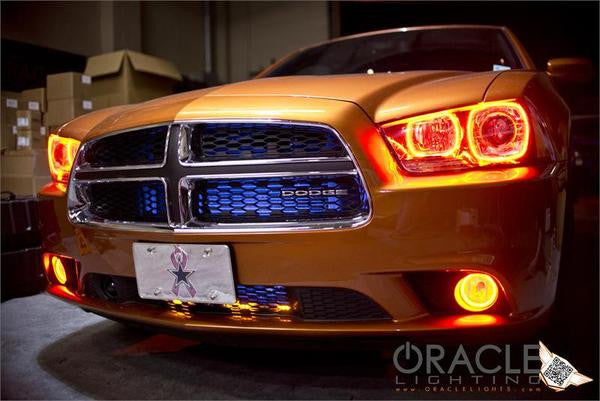 Front end of an orange Dodge Charger with amber LED headlight halo rings installed.