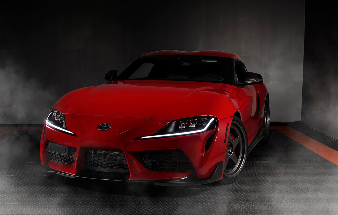 Three quarters view of a red Toyota Supra with white headlight DRLs.