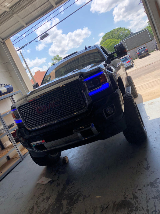 Front end of a GMC Sierra with blue headlight DRLs.