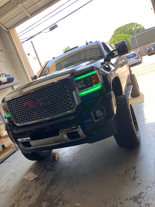 Front end of a GMC Sierra with green headlight DRLs.