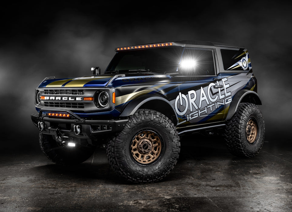 Three quarters view of ORACLE Lighting wrapped Ford Bronco with Integrated Windshield Roof LED Light Bar System installed and set to amber LEDs.