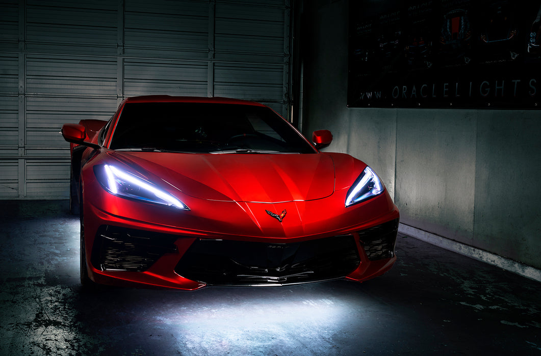Red Corvette in a garage with white headlight DRLs.