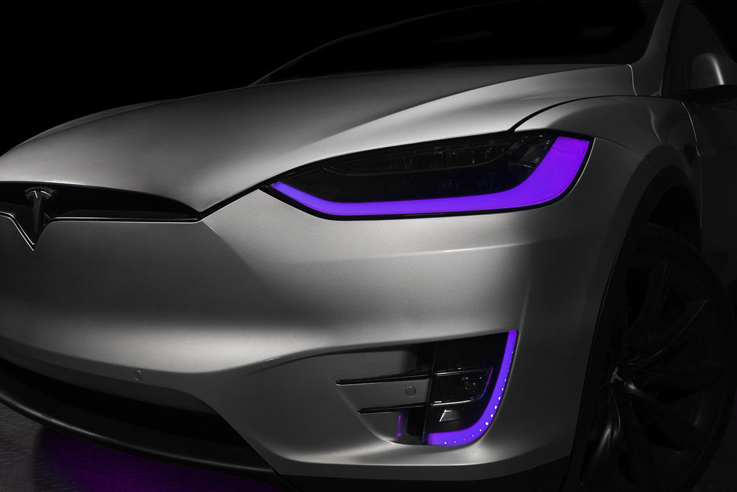 Close-up on the headlights and fog lights of a Tesla Model X with purple DRLs.