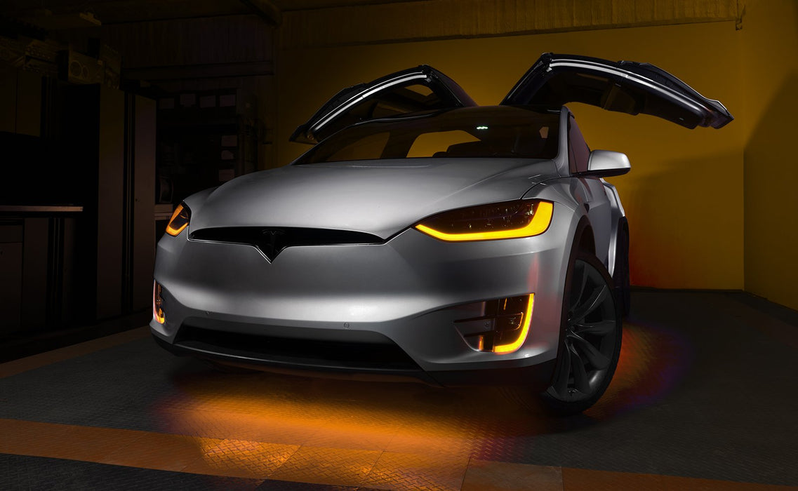 Silver Tesla Model X with amber headlight and fog light DRLs.