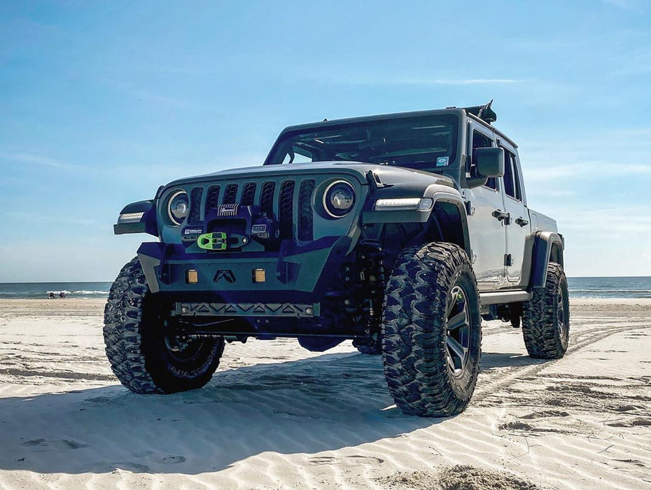 Three quarters view of a Jeep Gladiator on the beach with Oculus Headlights installed.